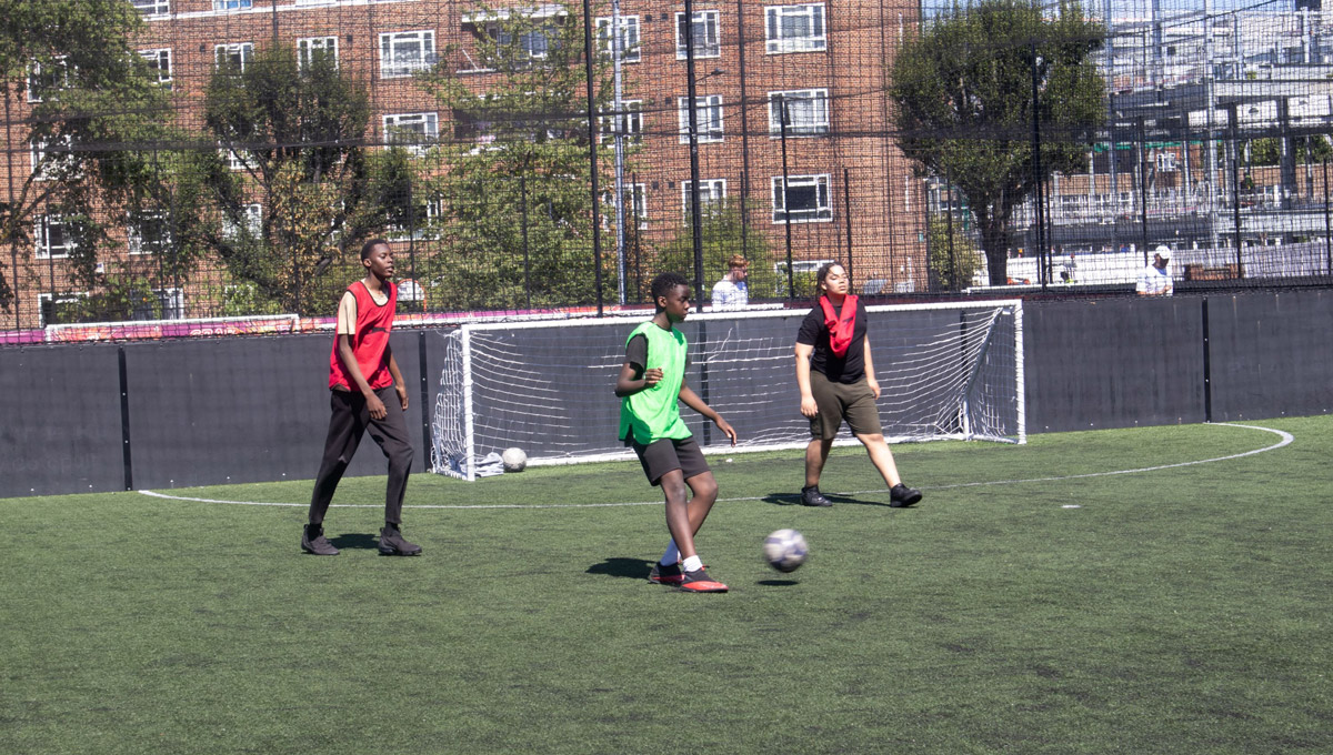 3 male children playing football outside