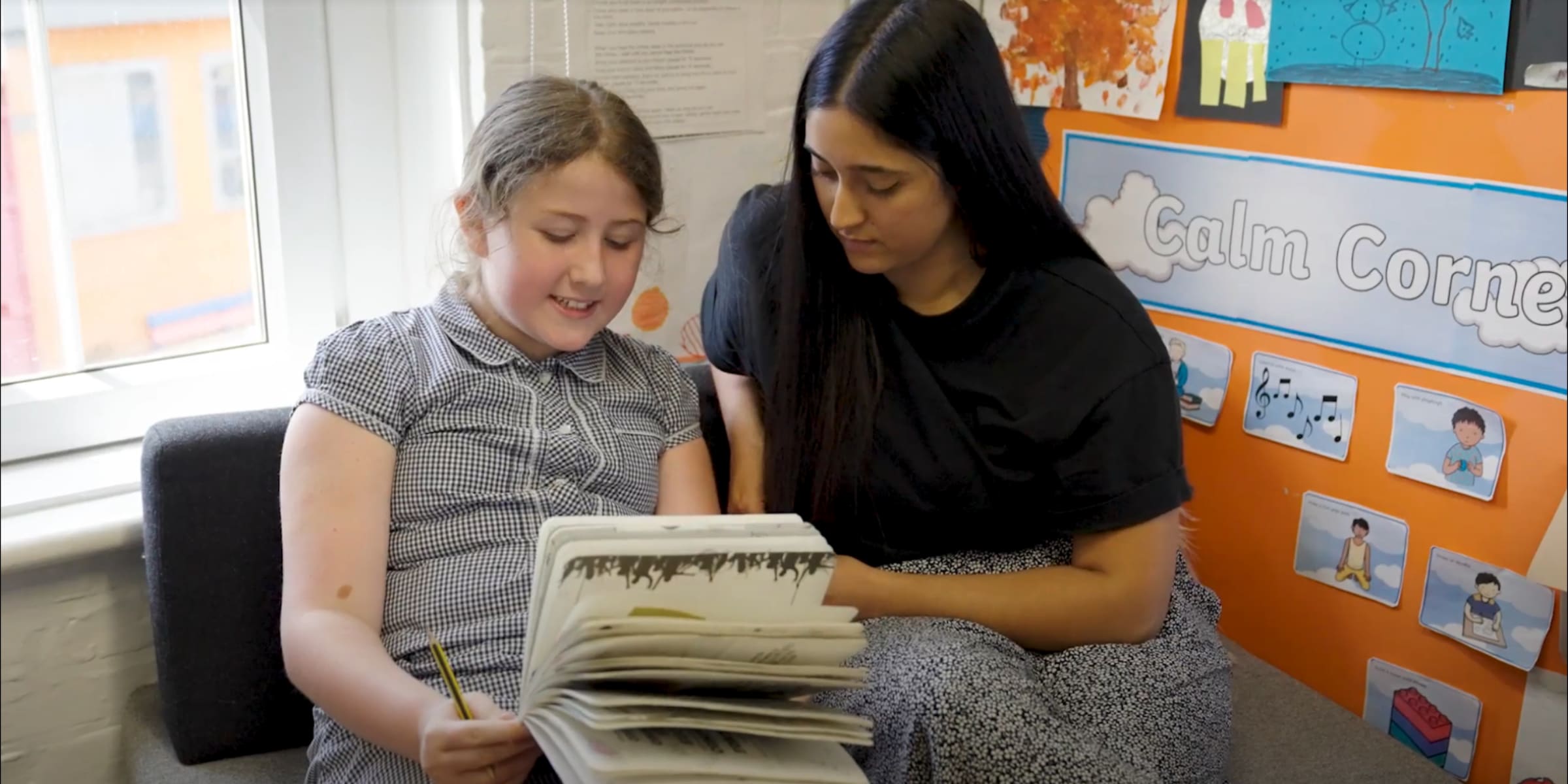 female child and adult reading together in school
